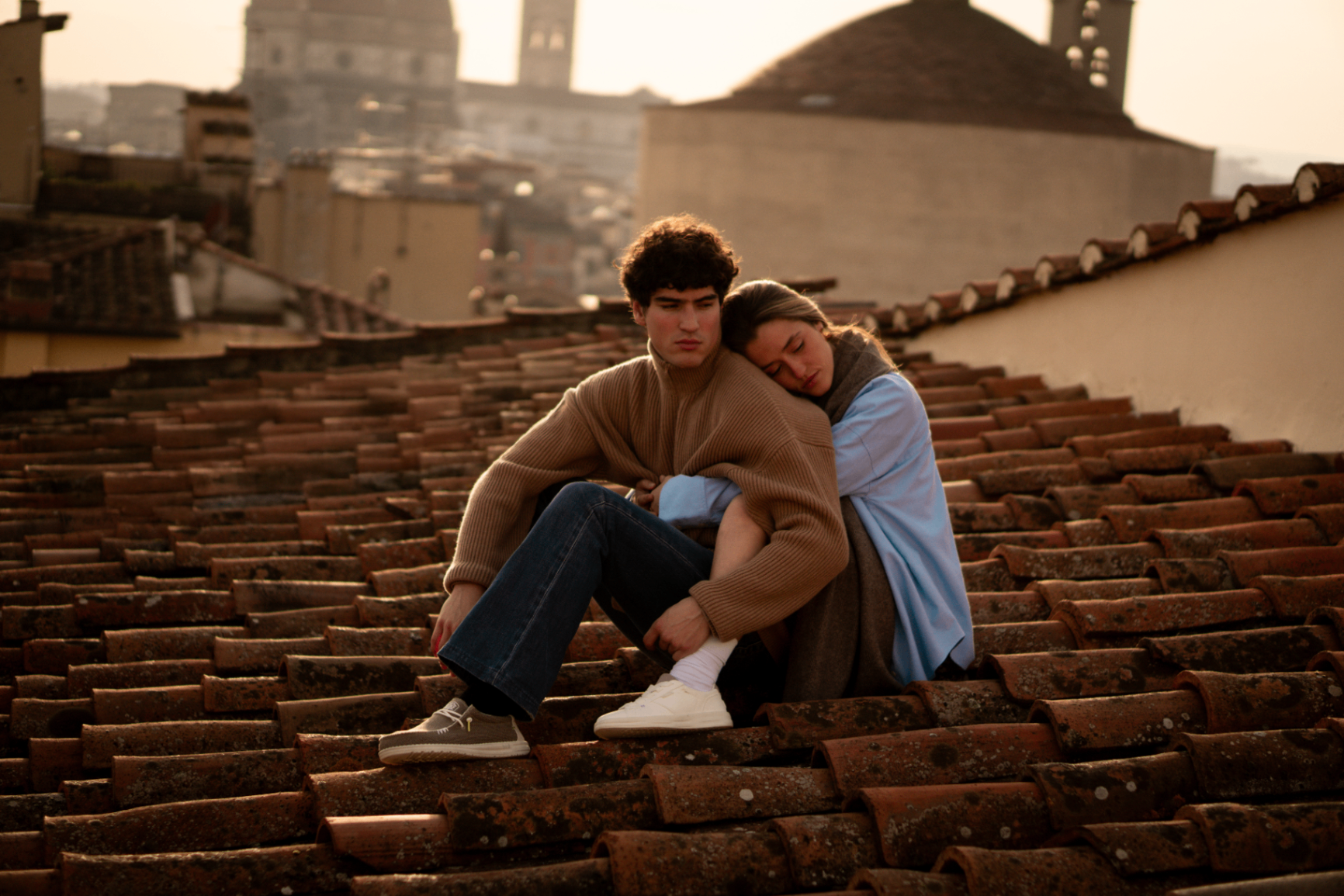 Two people on a rooftop at sunset